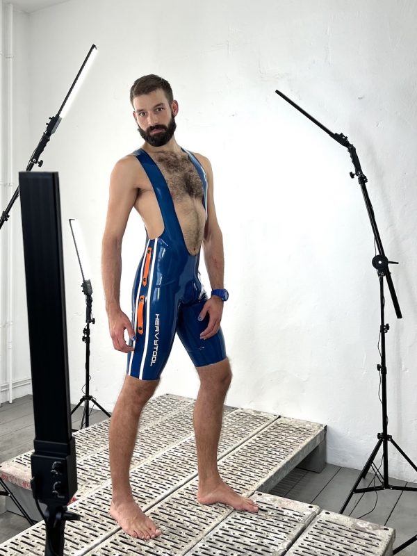 Latex / Rubber Fetisch Wrestlerbody, in transparent blau mit weißen Seitenstrifen, Logo und orangen Design Elementen. Für Männer, Kerle Boys und Queers